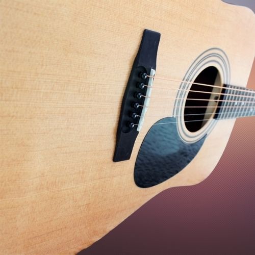 Close-up of an acoustic guitar with a focus on the soundhole and tuning pegs.