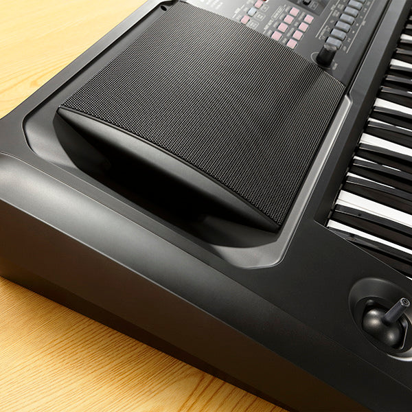 Close-up of a digital keyboard with foot pedal on a wooden surface