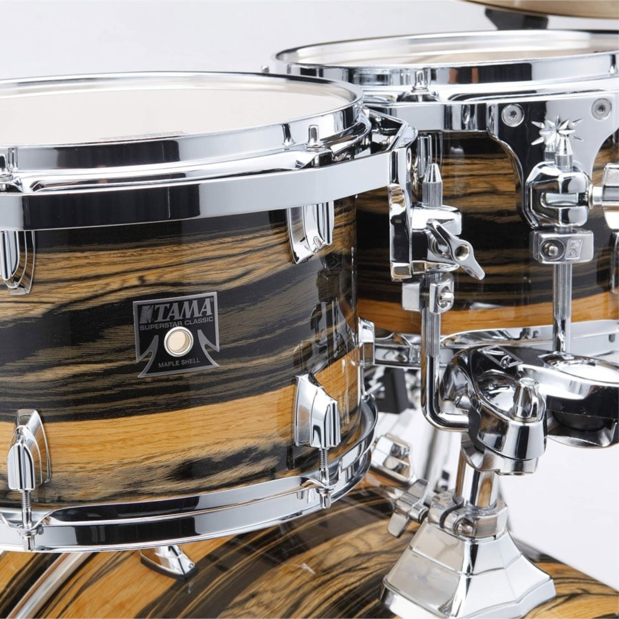 Close-up of a Tama drum set with wooden finish and chrome hardware.